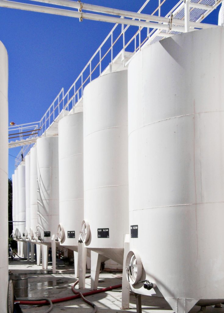 White storage tanks in an outdoor industrial setting.